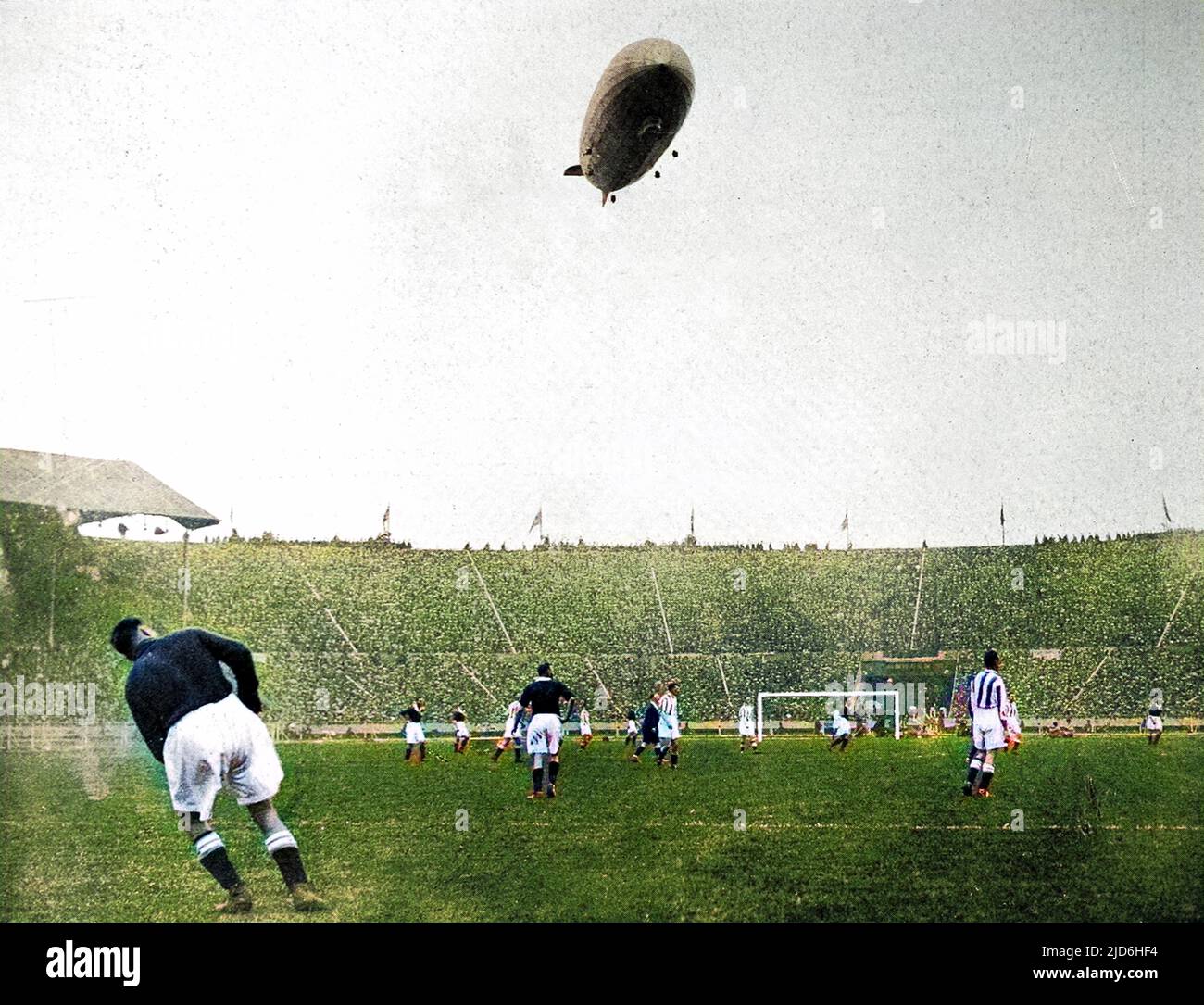 Stadio di Wembley, durante la città di Huddersfield vs Arsenal F.A. Finale di Coppa del 1930, con il 'Graf Zeppelin' nel cielo sopra. Si è riferito che il veliero tedesco "si è mantenuto molto basso sul terreno, sconcertando giocatori e spettatori con il ruggito assordante dei suoi motori”. Arsenal ha vinto la partita 2-0. Versione colorata di: 10219005 Data: 1930 Foto Stock