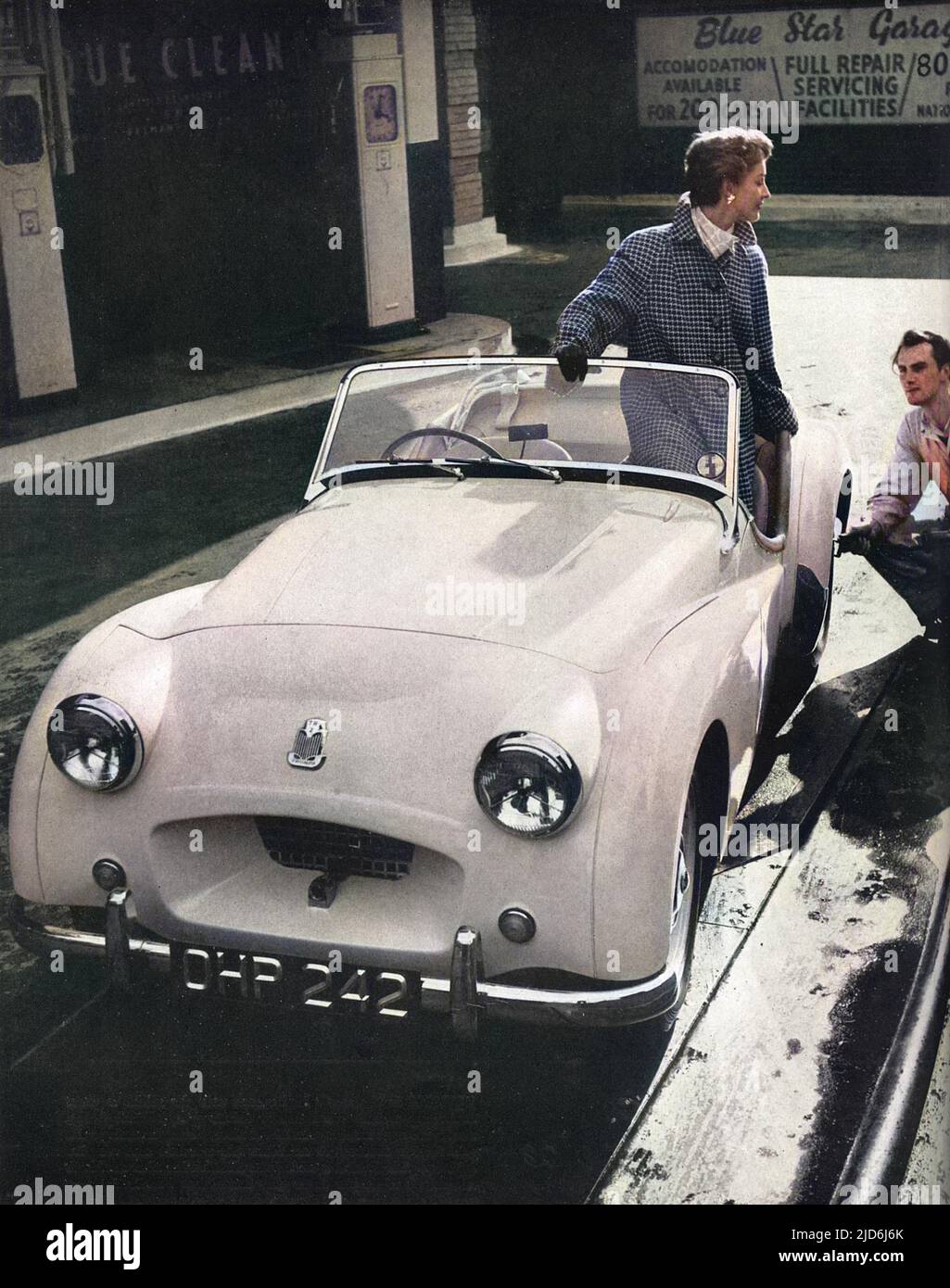 Una ragazza che indossa un cappotto scozzese verde e bianco tweed con profonde maniche raglan e tasche a fessura disegnate da Moorcot, si siede in un Triumph 2 litri modello sportivo capace di ben oltre 100 mph! Versione colorata di: 10511438 Data: 1953 Foto Stock