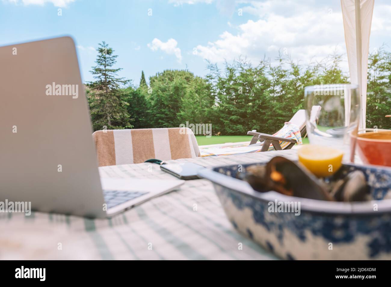 Scena di un tavolo sulla terrazza di una casa in estate con la piscina sullo sfondo. Scena estiva, sala da pranzo all'aperto. Spazio per fotocopie e grafica Foto Stock