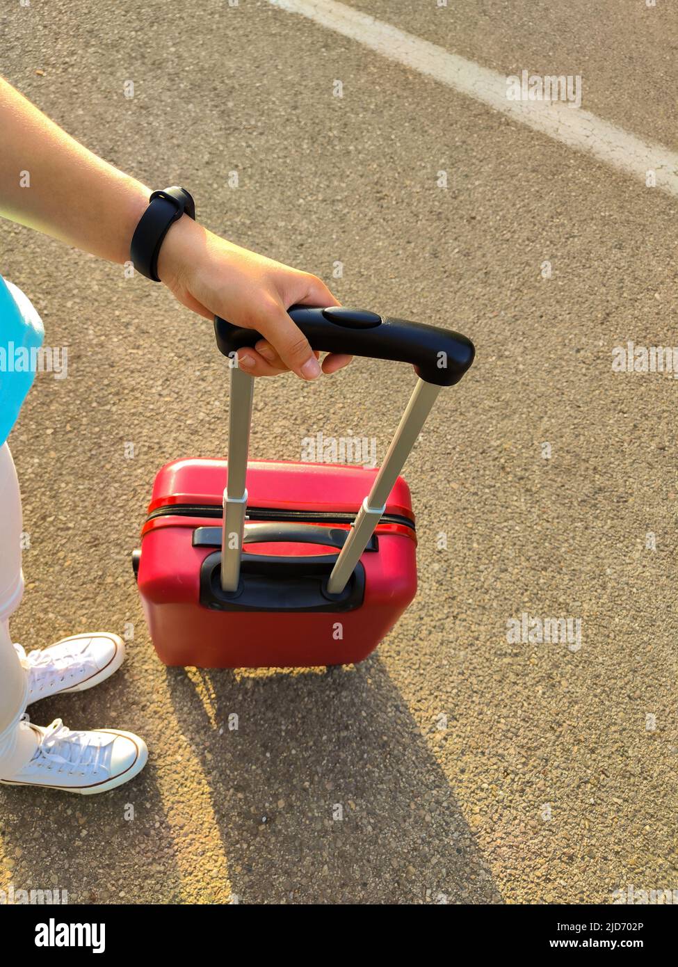 giovane donna con una valigia rossa in mezzo alla strada Foto Stock