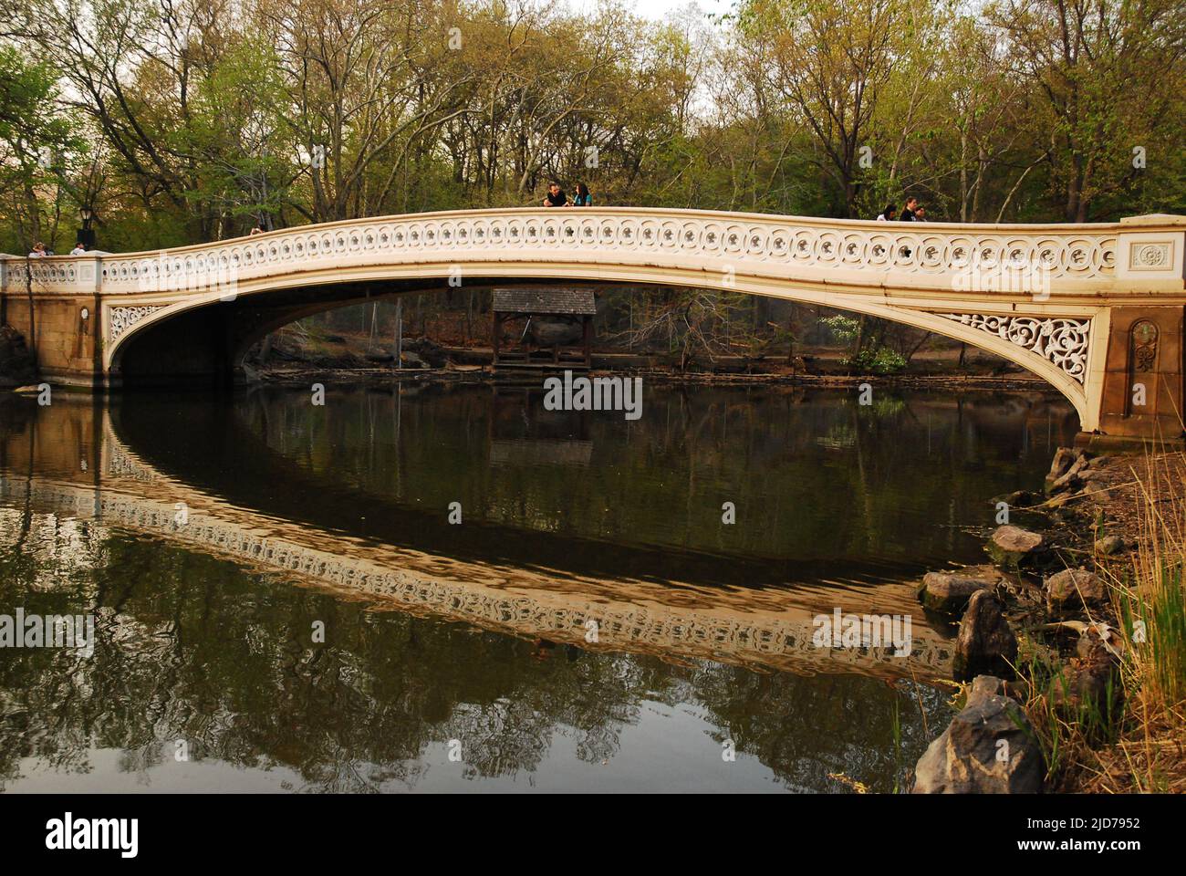 Il grazioso Bow Bridge, nel Central Park di New York, si riflette nelle acque calme del lago del parco Foto Stock