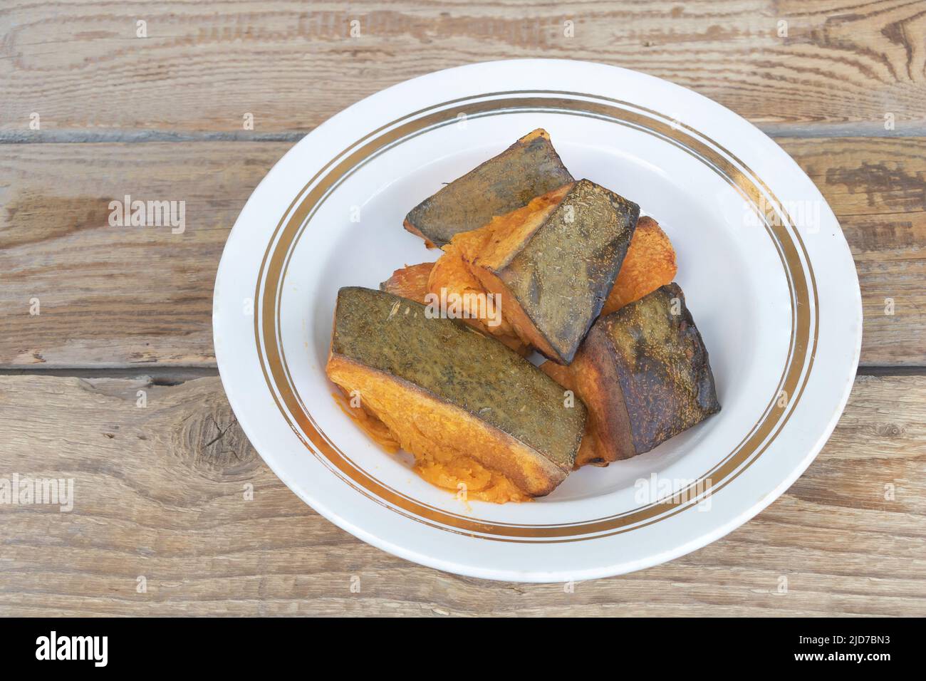 Primo piano di zucca cotta in un piatto con fondo in legno Foto Stock