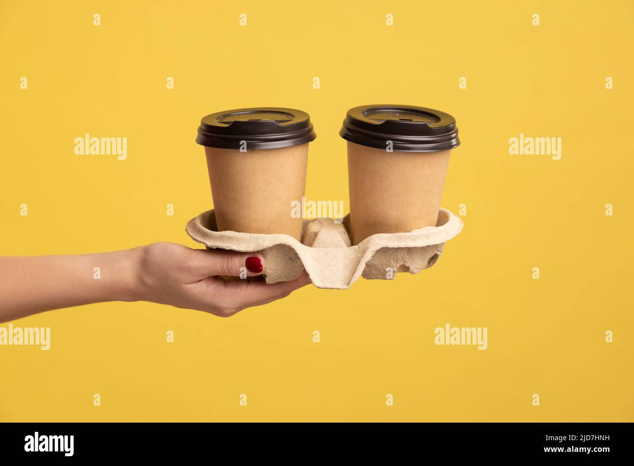 Profilo vista laterale primo piano della mano donna che tiene e mostra tazza di tazza calda tazza da asporto bevanda in mano, pausa caffè al lavoro. Studio interno girato isolato su sfondo giallo. Foto Stock