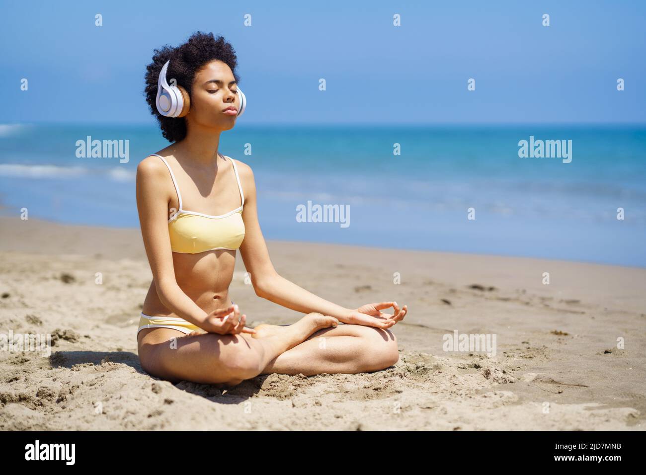 Tranquilla donna nera meditating in posa di loto su sabbiosa spiaggia Foto Stock