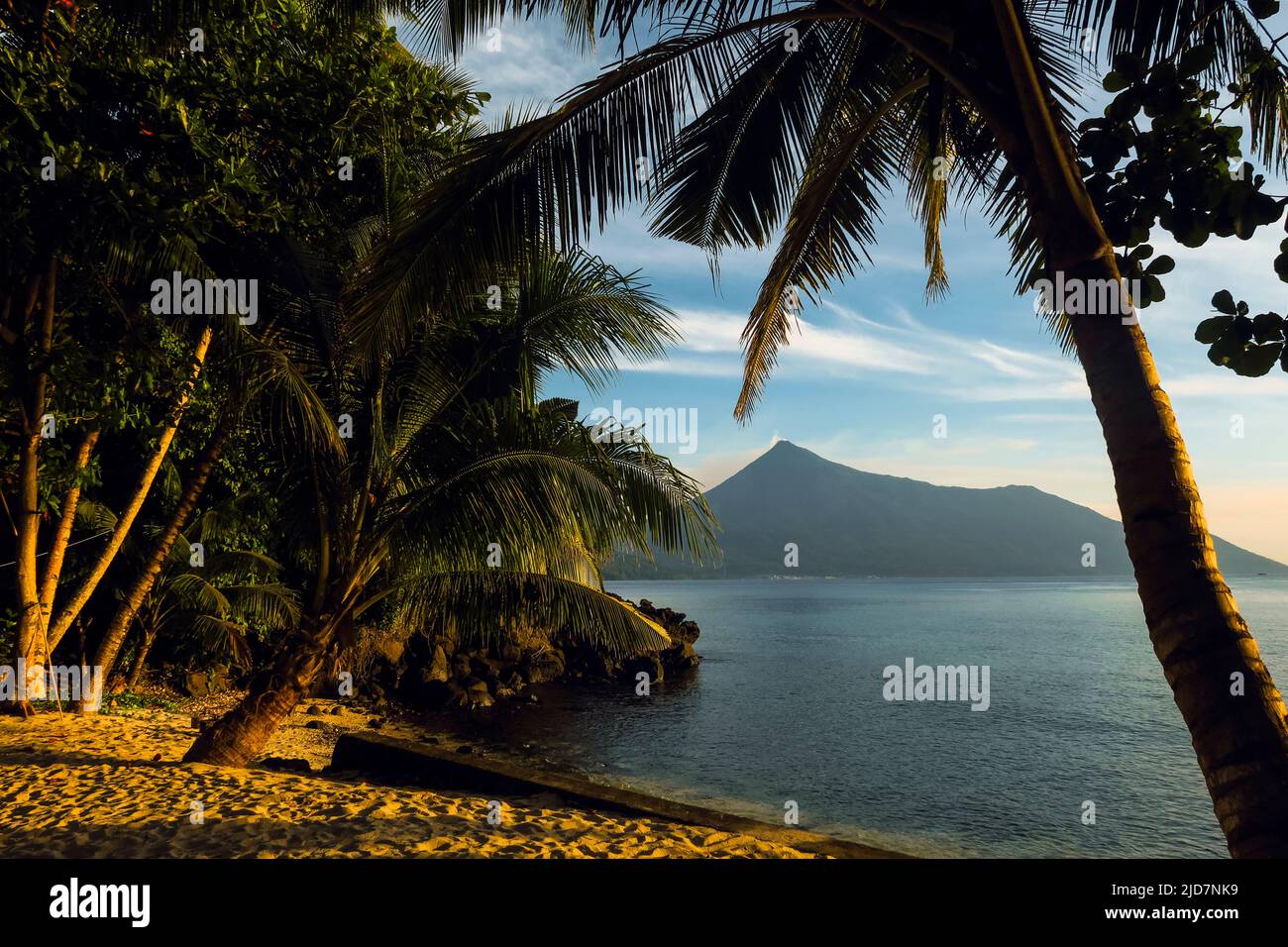 Vista a nord con palme e tramonto da Kalea Beach al vulcano attivo Karangetang. Kalea, Siau Island, Sangihe Arcipelago, Nord Sulawesi, Indonesia Foto Stock