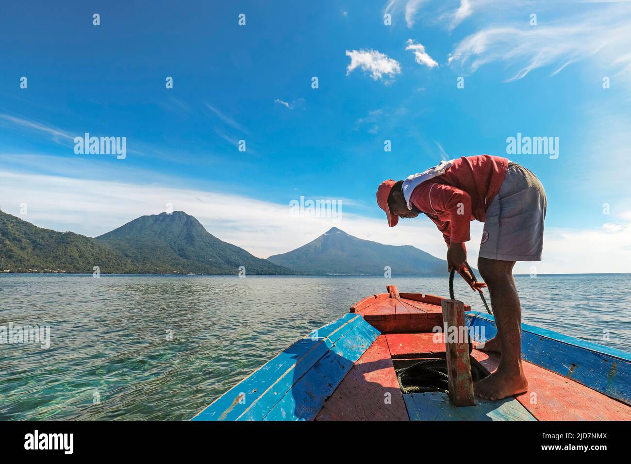 Gita in barca capitano al largo di Siau con l'Isola di Buhias e il vulcano Karangetang oltre. Isola di Siau, Arcipelago di Sangihe, Sulawesi settentrionale, Indonesia Foto Stock