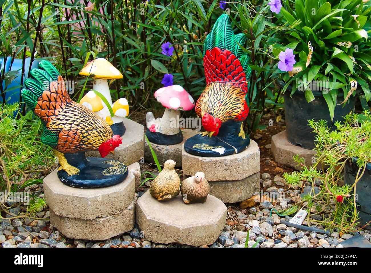 Ornamenti da giardino di polli colorati, pulcini e sgabelli in un giardino in Thailandia Foto Stock