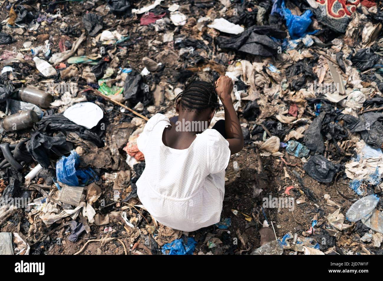 Vista dall'alto di una ragazza africana circondata da rifiuti in cerca di materiale riciclabile Foto Stock