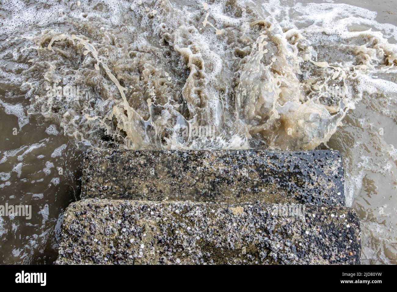 Onde di mare tempestose che si infrangono contro scale di pietra, vista dall'alto. Foto Stock