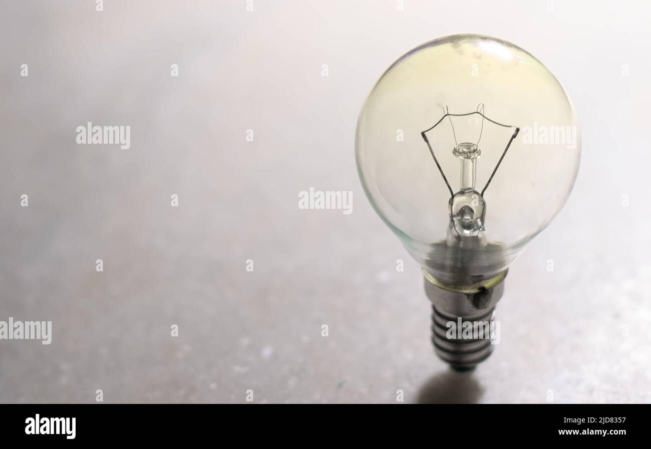 Una piccola lampadina a incandescenza o una lampada su una superficie rigida bianca Foto Stock