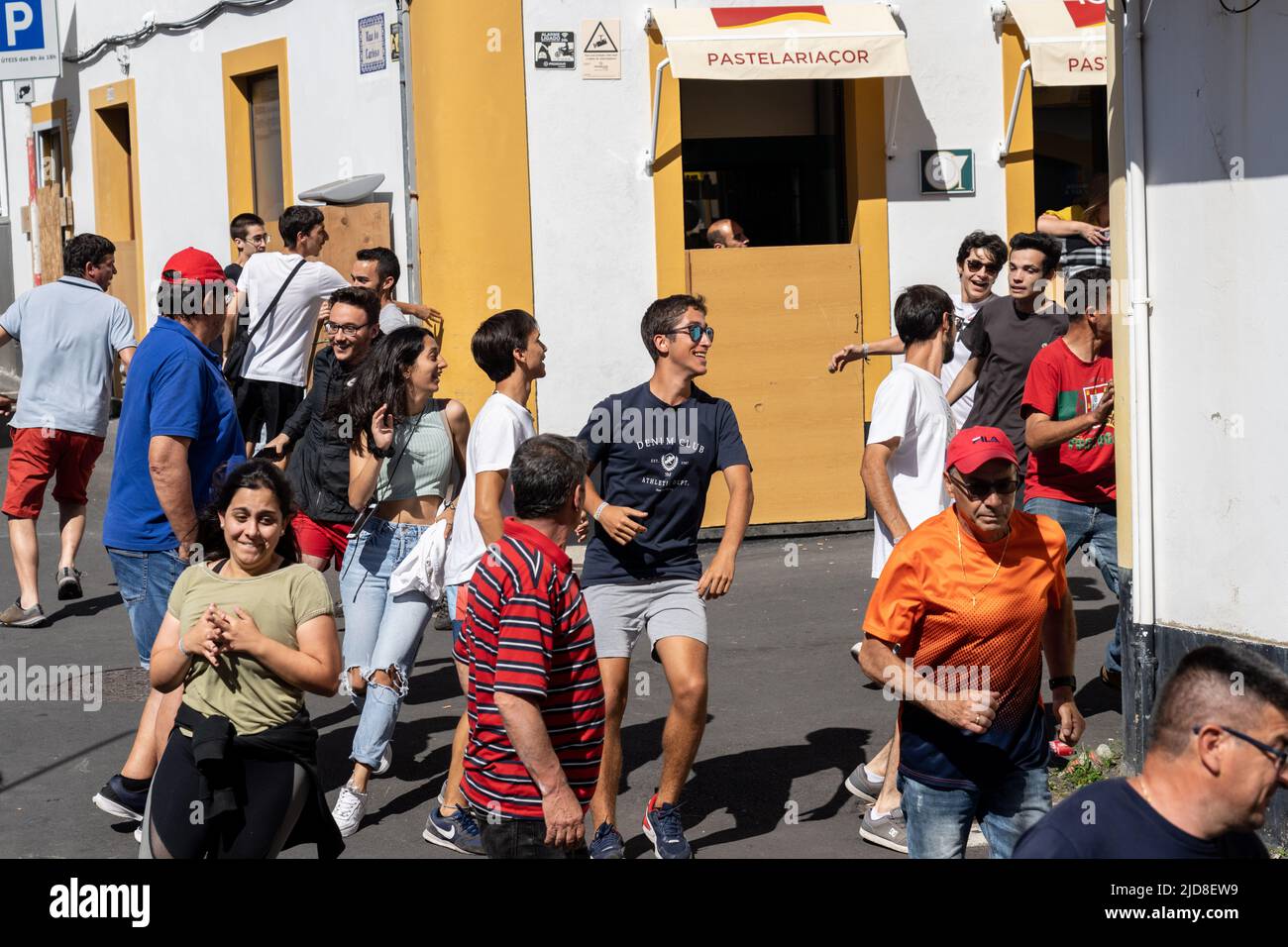 I residenti scappano via come un toro corre sciolto attraverso le strade durante una tourada a corda, anche chiamato un toro su corda al festival Sanjoaninas, 18 giugno 2022 ad Angra do Heroísmo, isola di Terceira, Azzorre, Durante l'evento unico delle Azzorre un toro legato ad una lunga corda corre sciolto mentre i partecipanti tentano di distrarre o correre dal toro. Foto Stock