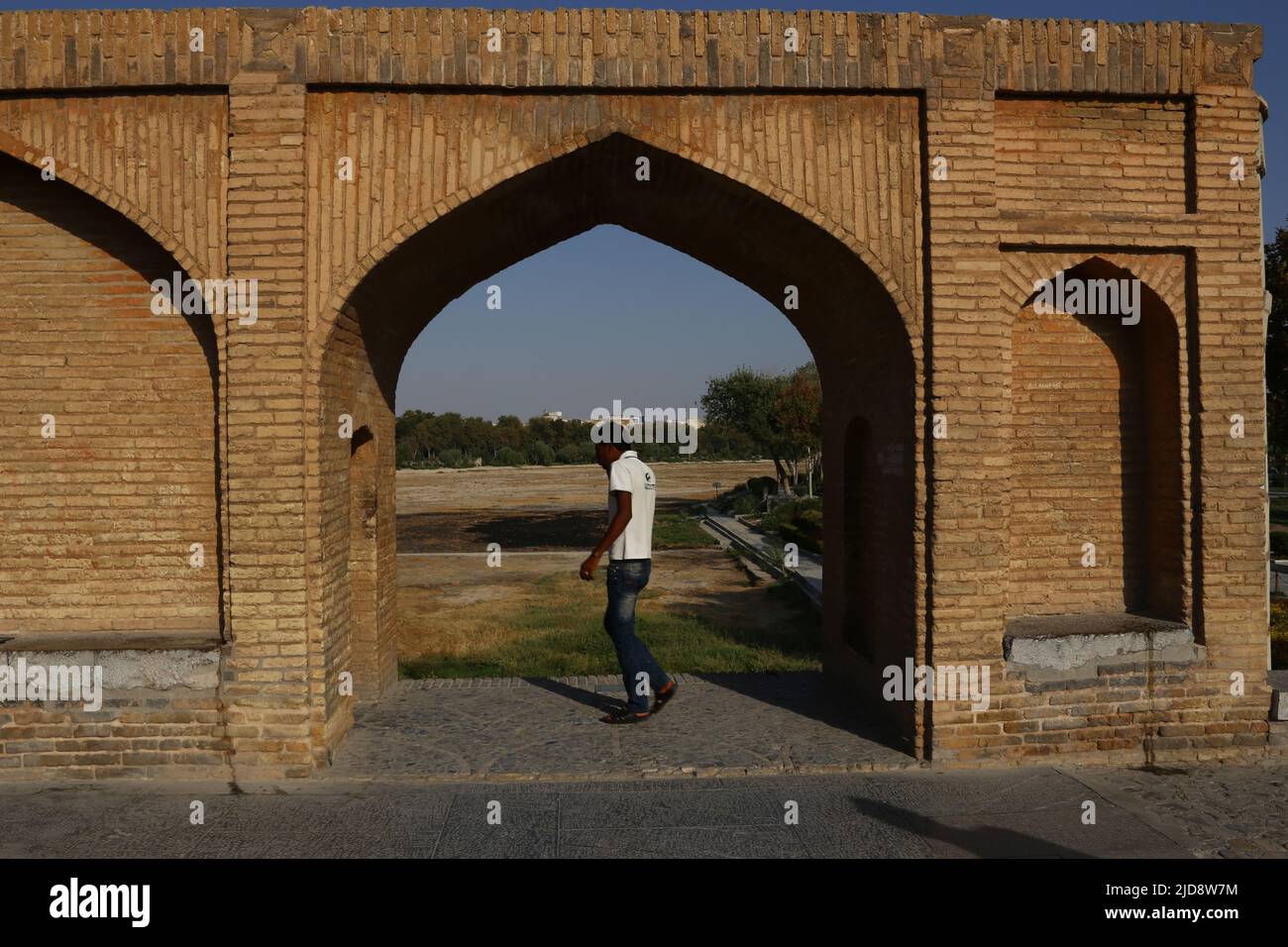 Allah-Verdi-Khan-Brücke a Isfahan, Iran. Auf persisch heißt sie si-o-se Pol. Die Brücke hat zwei Etagen und überspannt den Zayandeh Rud. Dado Brücke cappello 33 Bögen. Der Blick geht durch einen Steinbogen auf den si-o-se Pol. Im Vordergrund ist eine person zu sehen. Foto Stock