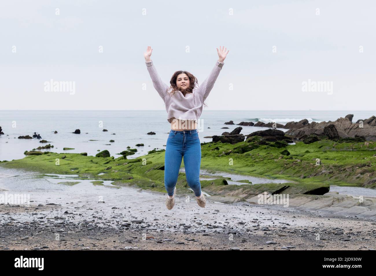 giovane donna che salta sulla spiaggia in primavera Foto Stock