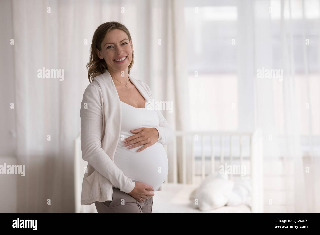 La donna incinta tocca il ventre grande guardando la fotocamera Foto Stock