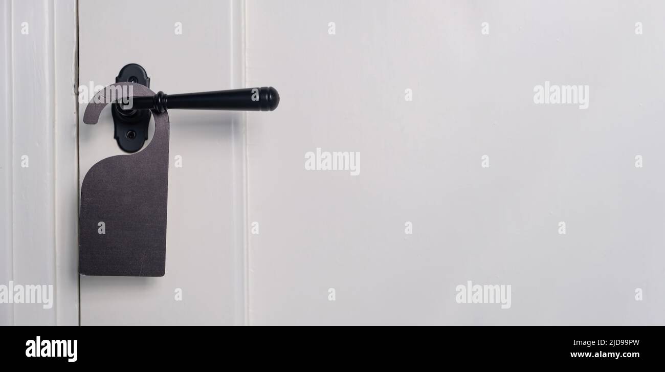 Appendiabiti in camera vuoto. Etichetta nera sulla maniglia della portiera posteriore chiusa, vista ravvicinata. Porta bianca in legno, spazio copia Foto Stock