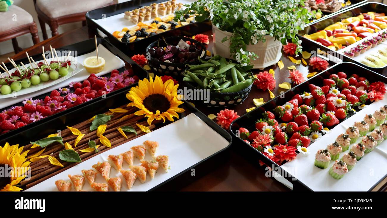 Selezione di antipasti su vassoi neri decorati con fiori e bacche. Foto Stock