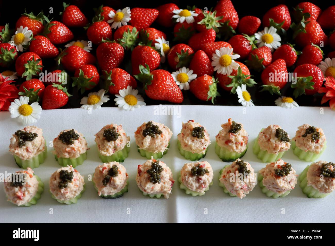 Coppe di cetrioli farcite con insalata di aragoste con caviale sul vassoio decorato con fragole. Foto Stock