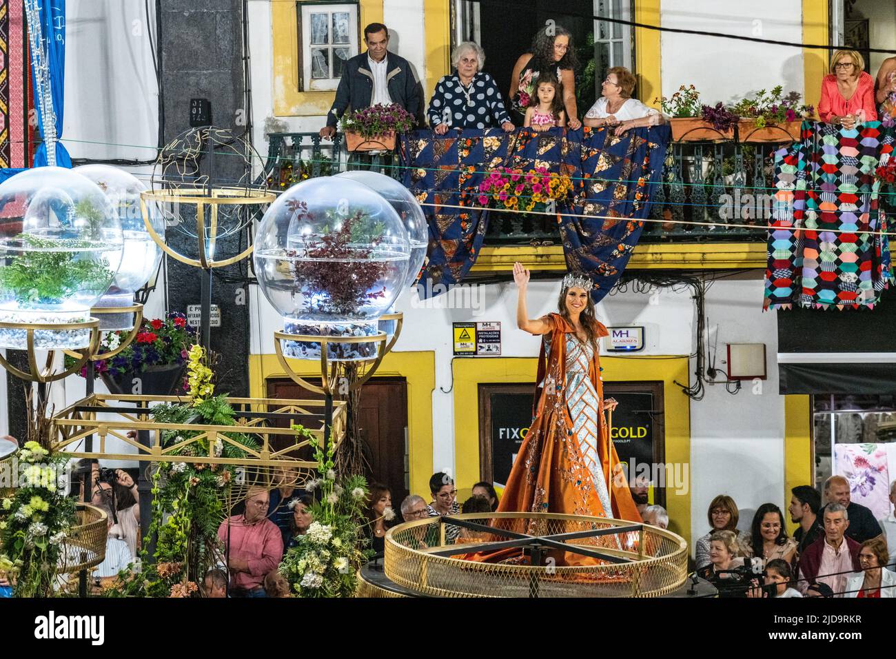 Una regina di bellezza ondeggia come lei cavalca un galleggiante oltre la Cattedrale del Santo Salvatore durante una sfilata in celebrazione del festival di Sanjoaninas, 17 giugno 2022 ad Angra do Heroísmo, isola di Terceira, Azzorre, Portogallo. Il festival segna il giorno di San Giovanni ed è celebrato con sfilate, corride e attività culturali. Foto Stock