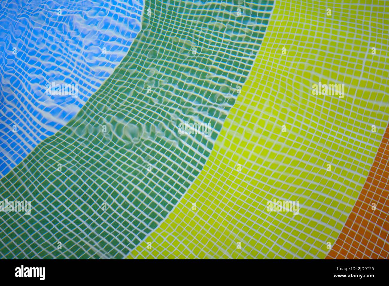 pavimento della piscina in colofrul asimmetrico a causa del movimento dell'acqua. piastrelle blu, giallo, verde, smaltate Foto Stock