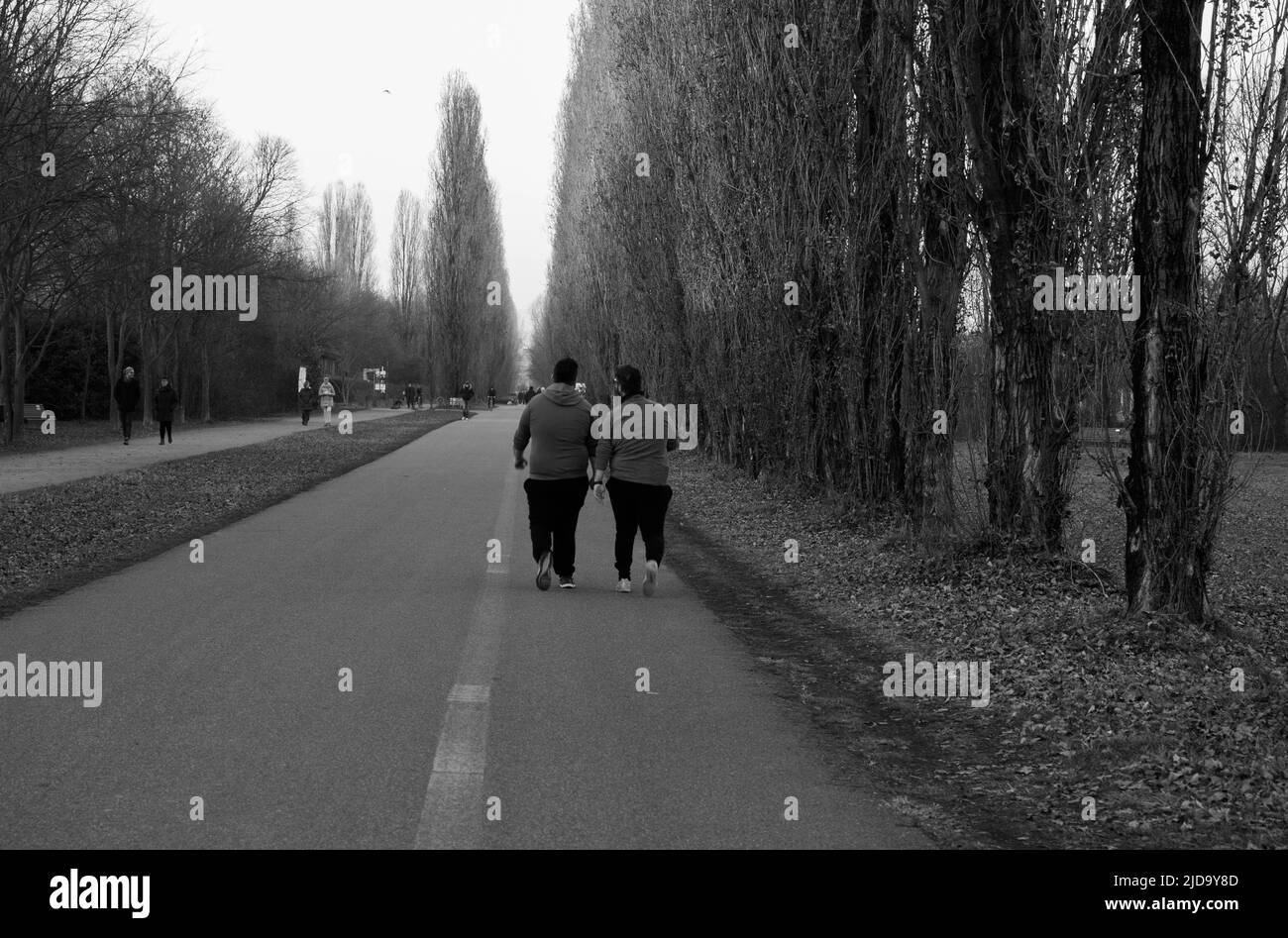 Bresso, Milano, 04-22-2018Two uomini in sovrappeso sparati dietro, corrono allo stesso ritmo in un parco pubblico formando un'immagine simmetrica. Foto Stock