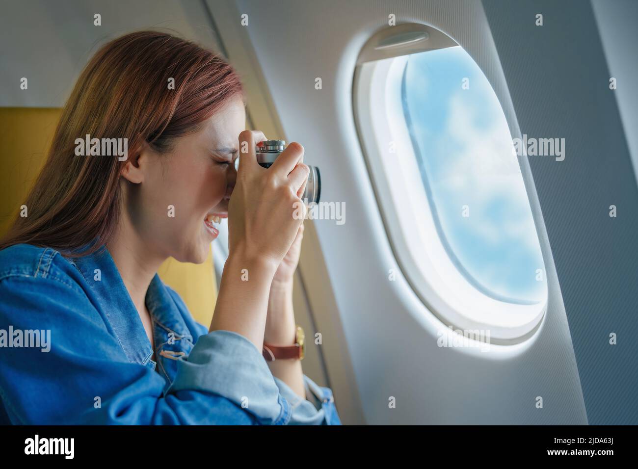 Viaggio, Ritratto di una sorridente turista asiatico con una macchina fotografica che scatta foto del cielo durante il suo volo Foto Stock
