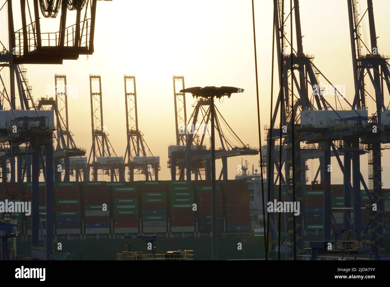 Vista alla silhouette di alta costruzione di grandi gru a portale in posizione orizzontale in attesa di carico funzionamento delle navi container nel porto di Pireo Foto Stock
