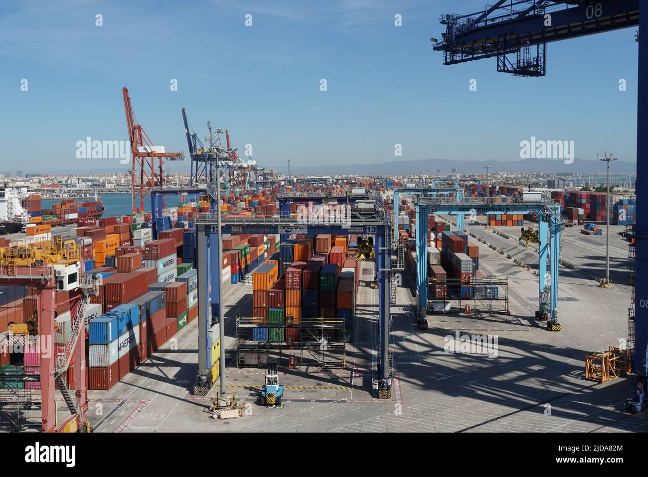 Terminal container con container stivati da diversi caricatori e gru a portale a Valencia. Foto Stock