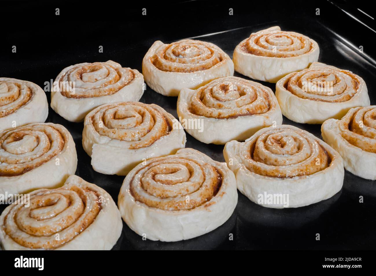 Dodici ciambelle di cannella non cotte in forno elettrico Foto Stock