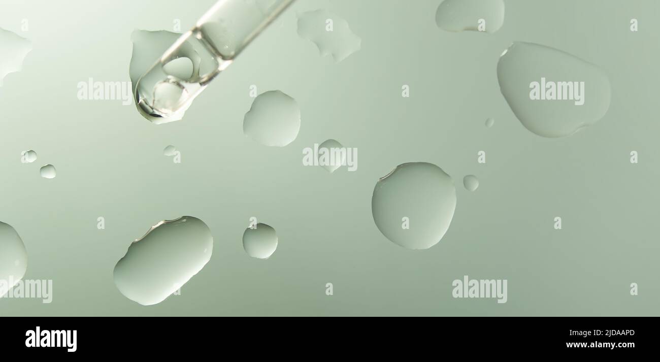 Pipettare con una goccia di olio essenziale per la cura della pelle in un contenitore di vetro su sfondo chiaro. Composizione minimalistica su una superficie di vetro. Foto di alta qualità Foto Stock