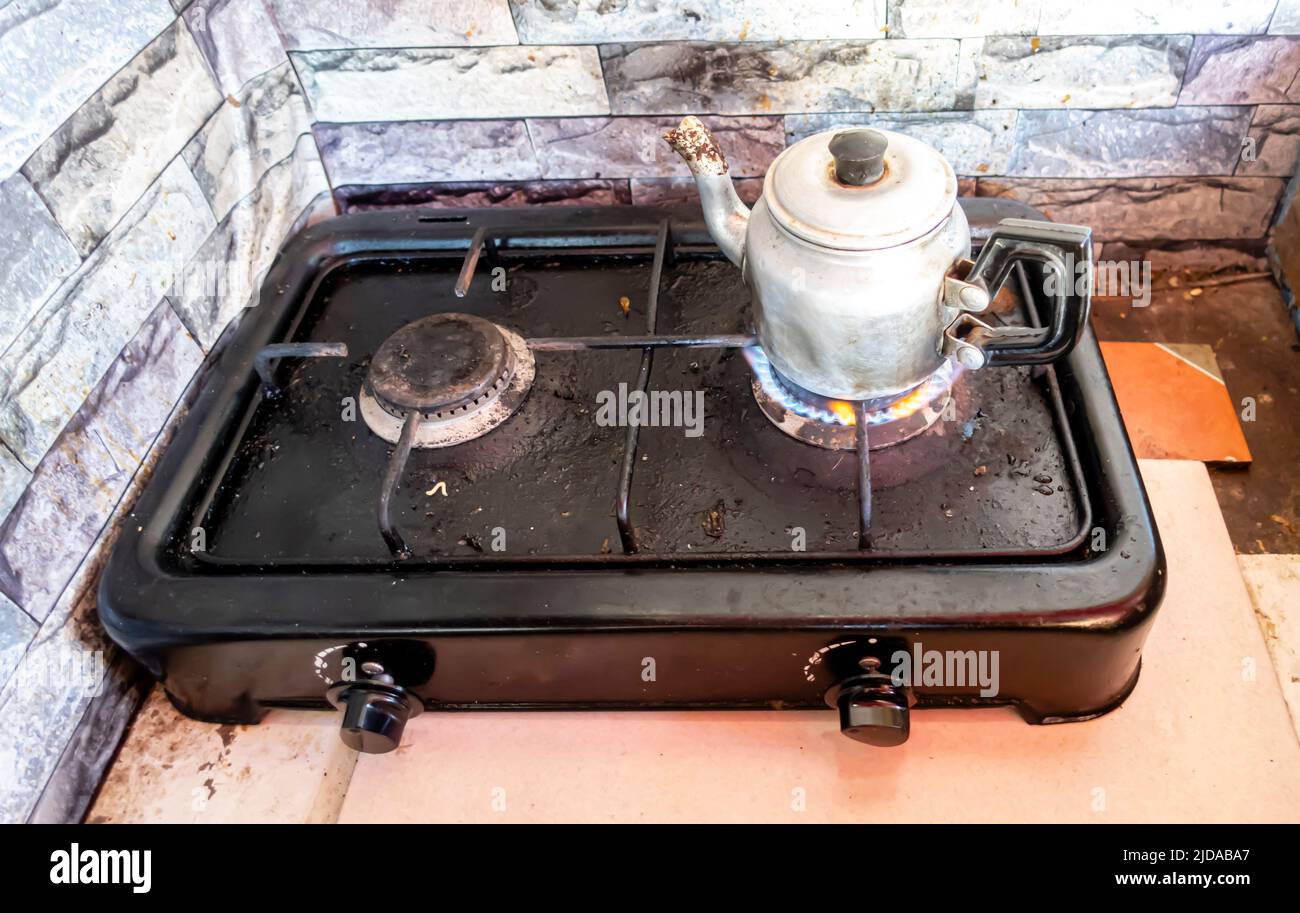 Tea pot su un fuoco a gas su una doppia piastra a gas semplice da cucina Foto Stock