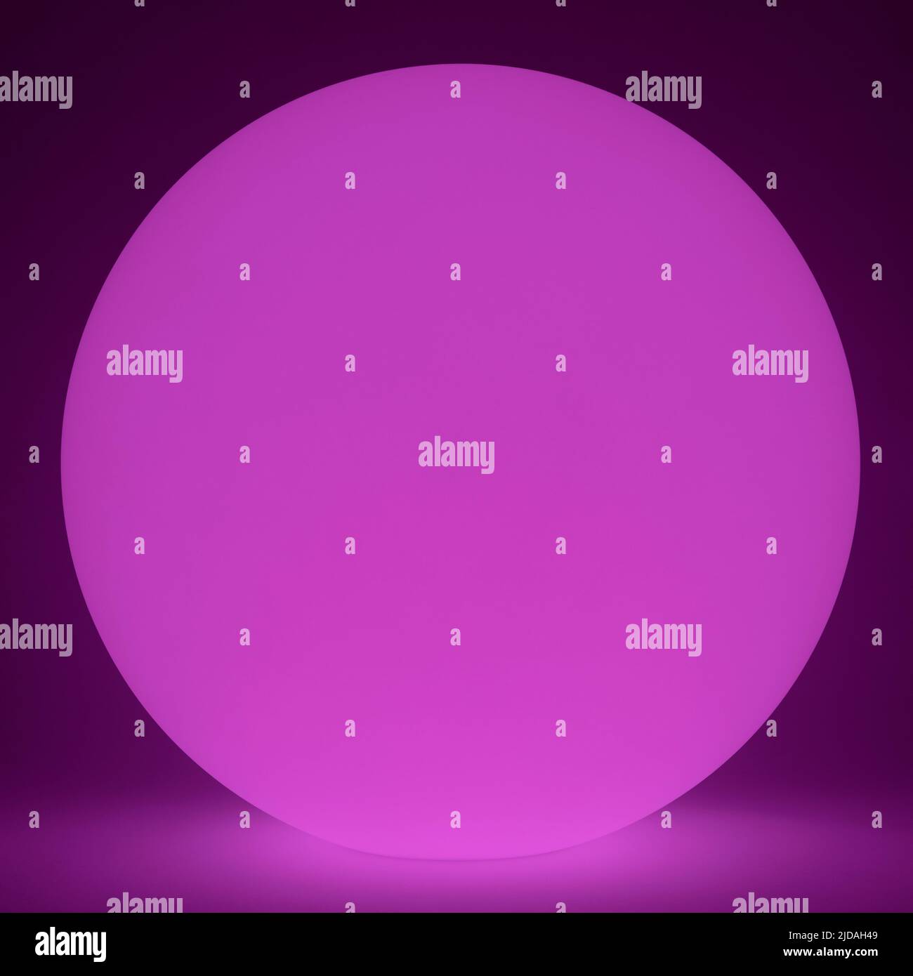 Un cerchio di luce viola rosa su uno sfondo più scuro, luci a LED Foto Stock