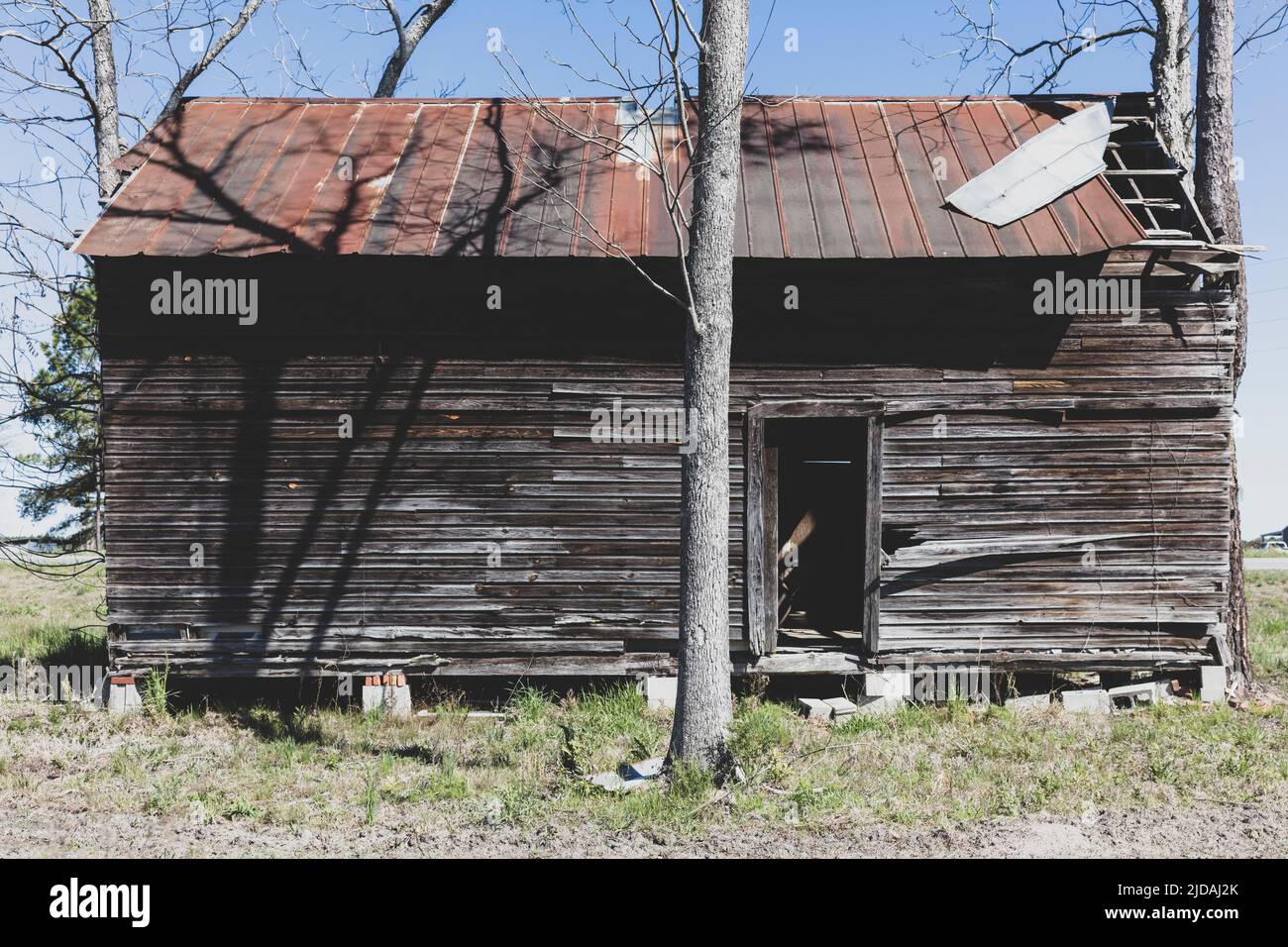 Casale in legno abbandonato con tetto di arrugginita in stagno. Foto Stock
