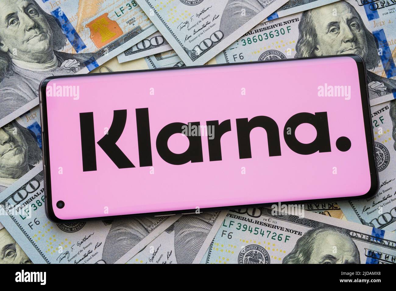 Logo dell'app Klarna visto sullo schermo dello smartphone piazzato su bollette in dollari. Concetto per l'app di credito. Stafford, Regno Unito, giugno 19 2022 Foto Stock