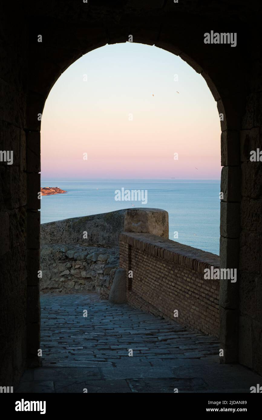 Tramonto visto attraverso l'arco del castello di Santa Barbara, Alicante, Spagna. Foto Stock