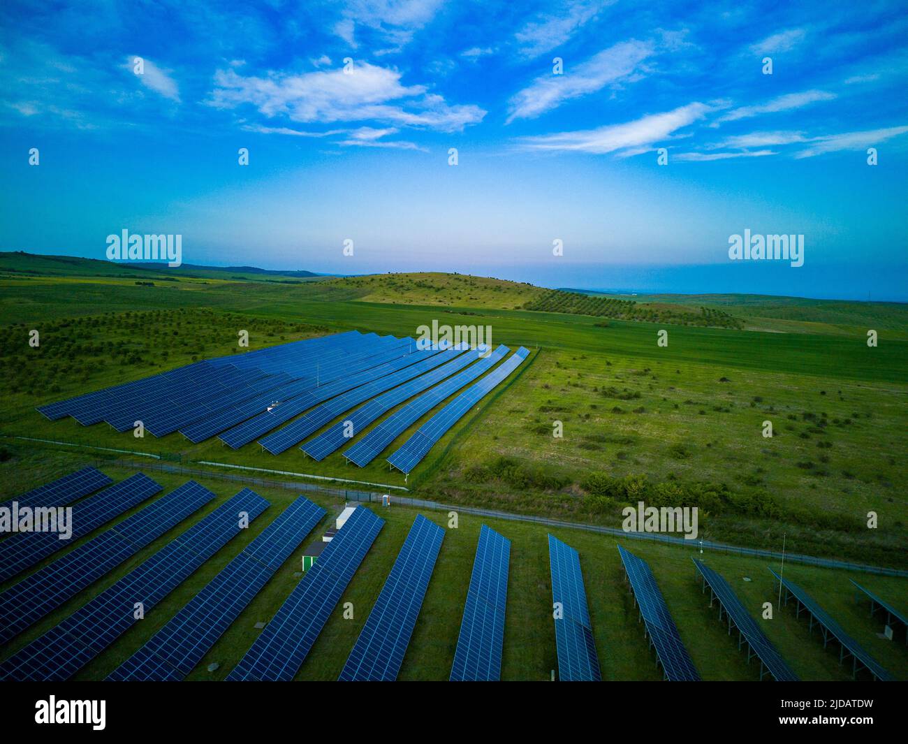 Moderni pannelli solari eco-compatibili per generare energia dai raggi del sole sono installati in prati infiniti con erba verde, sotto il cielo blu con brigh Foto Stock
