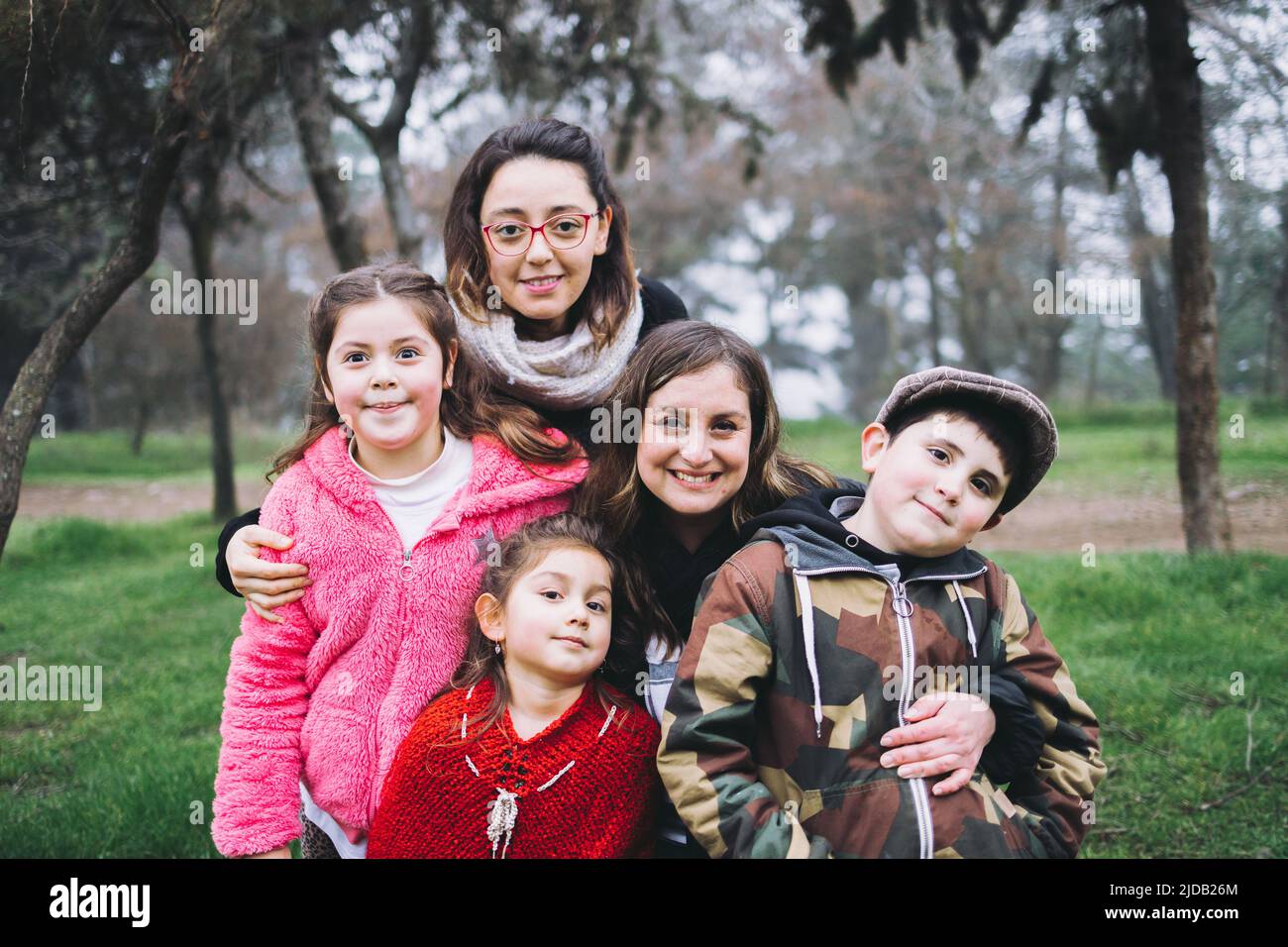 Genitori dello stesso sesso con loro figlio e figlie che ridono e abbracciano nel parco. Famiglia LGBT omoparentale Foto Stock