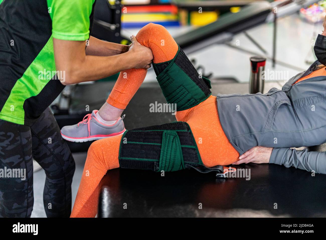 Una donna paraplegica che lavora alla flessione dell'anca mentre il suo allenatore fa la coda fisica: Edmonton, Alberta, Canada Foto Stock