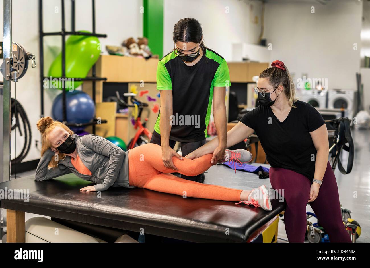 Una donna paraplegica che lavora alla flessione dell'anca mentre il suo allenatore fa la coda fisica: Edmonton, Alberta, Canada Foto Stock