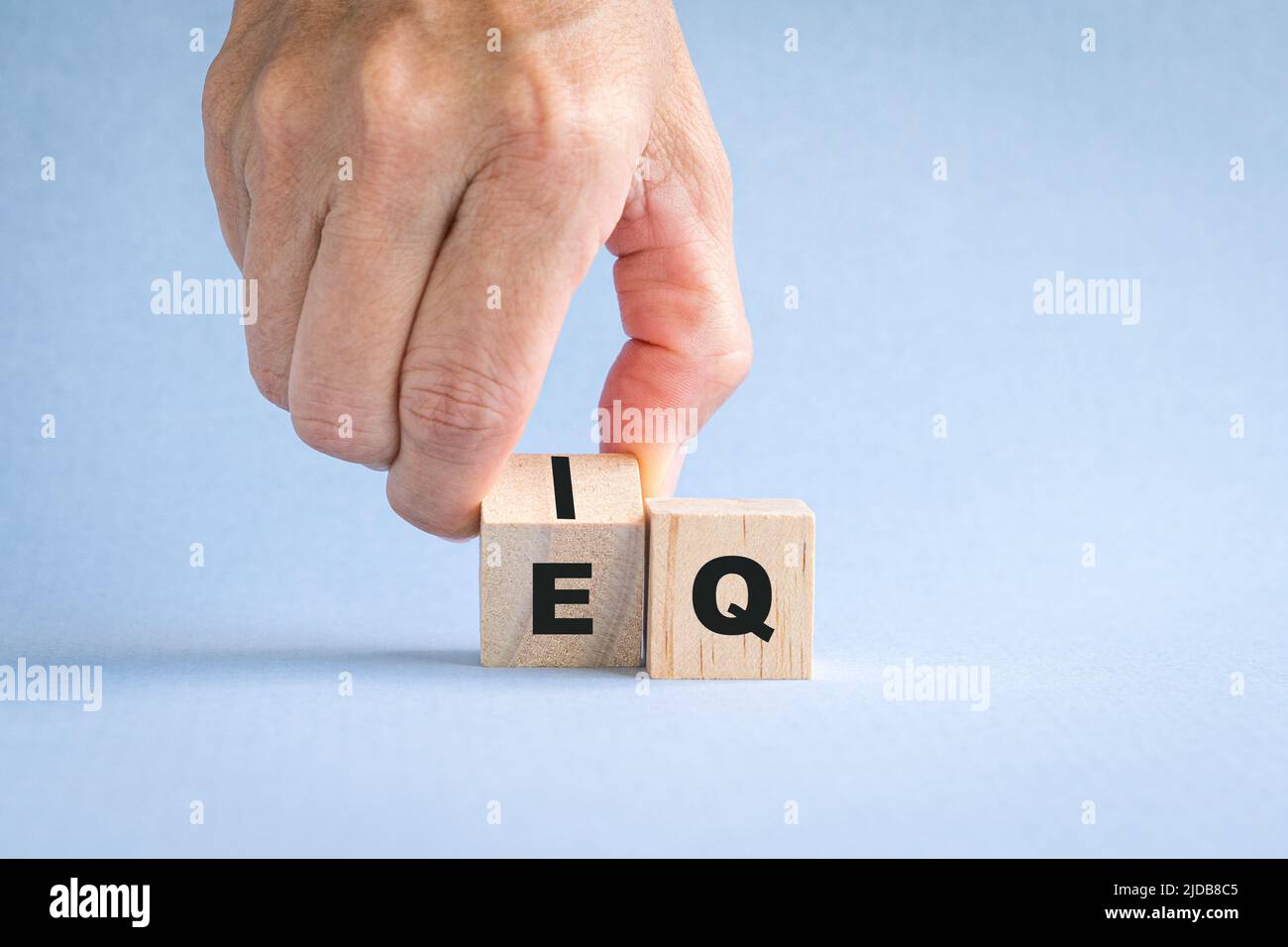 Le dita ribaltano il cubo di legno con la parola da IQ a EQ. Foto Stock