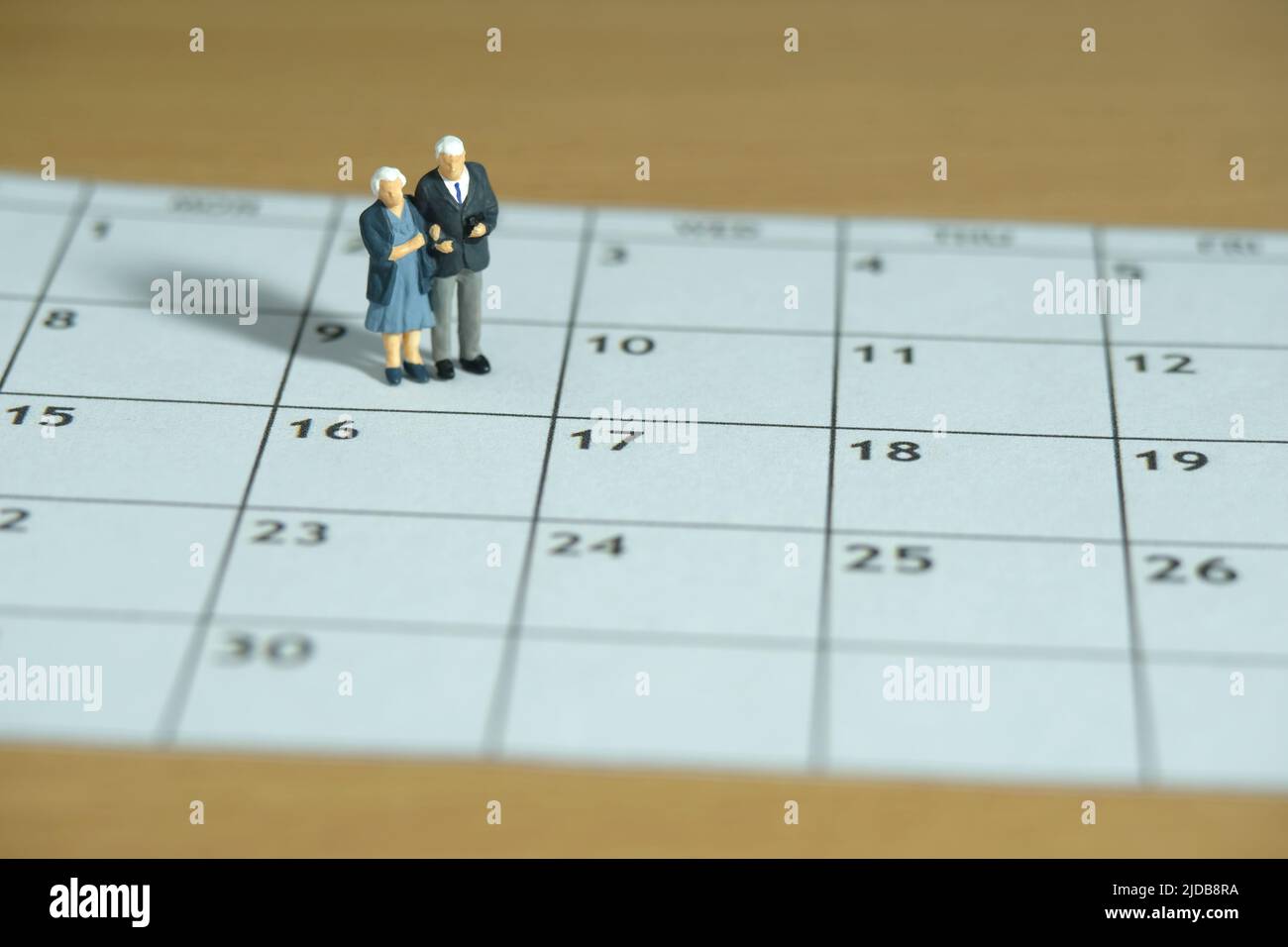 Persone in miniatura giocattoli fotografia concettuale. Coppia anziana in piedi sopra il calendario. Concetto di datazione. Foto immagine Foto Stock