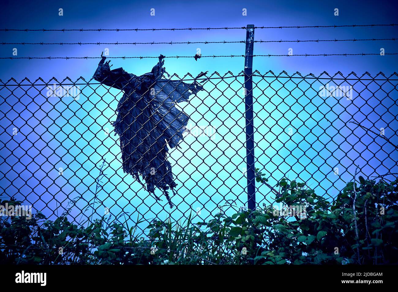 Sacchetto di plastica nero a forma di una vecchia strega impigliata sulla recinzione di sicurezza Foto Stock