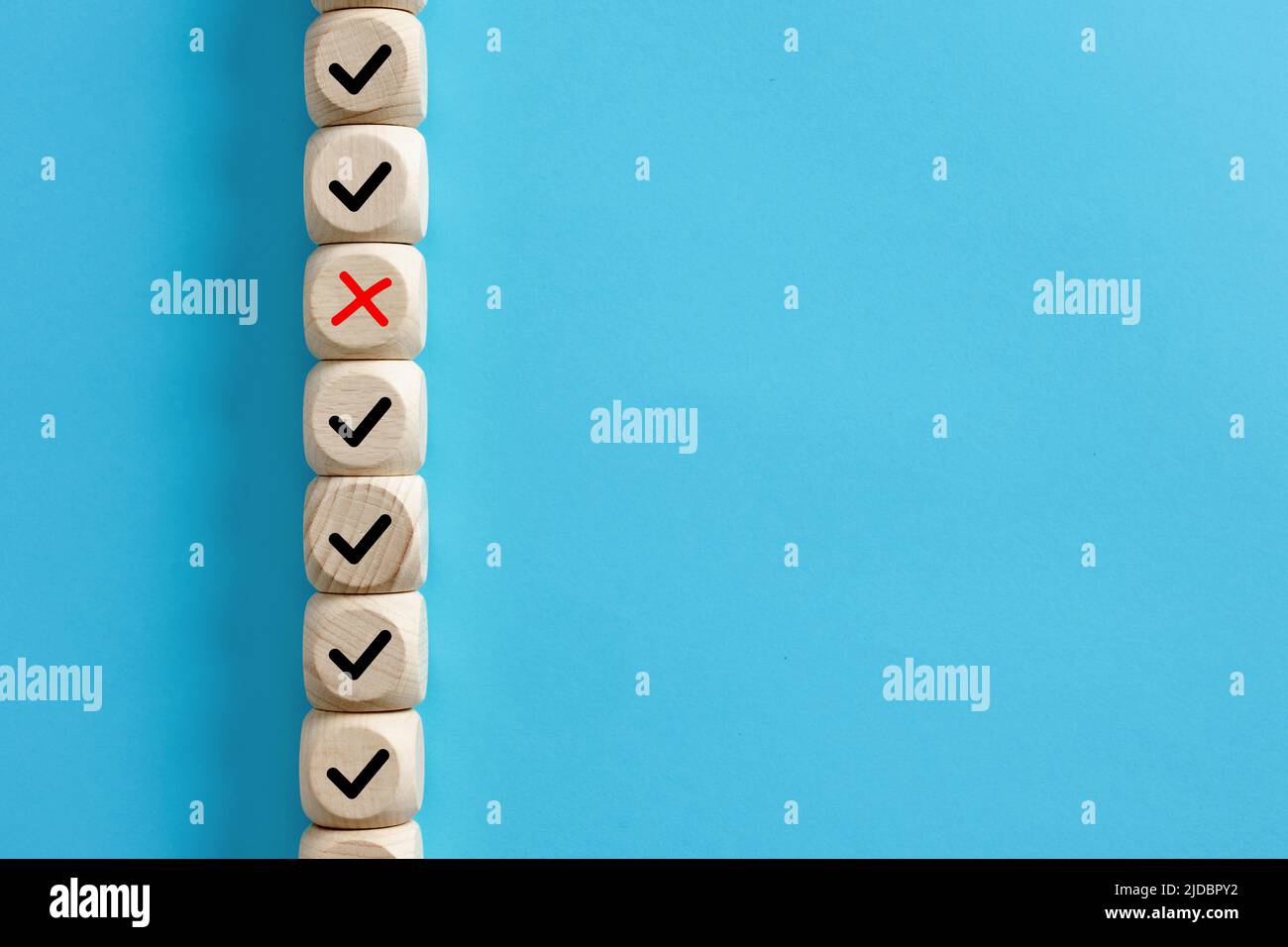 Il cubo di legno con il simbolo sbagliato a croce si distingue tra i cubi di legno con il segno di spunta a destra. Prendere la decisione sbagliata nel concetto di business. Foto Stock