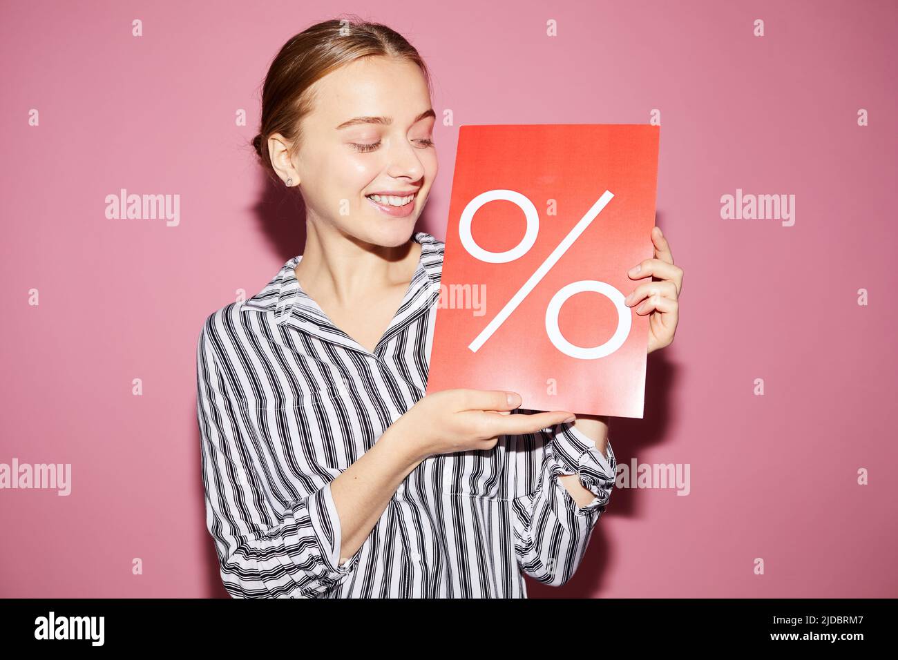 Un'attraente e positiva donna di vendita che tiene un banner percentuale mentre condivide le informazioni sull'offerta speciale in negozio Foto Stock