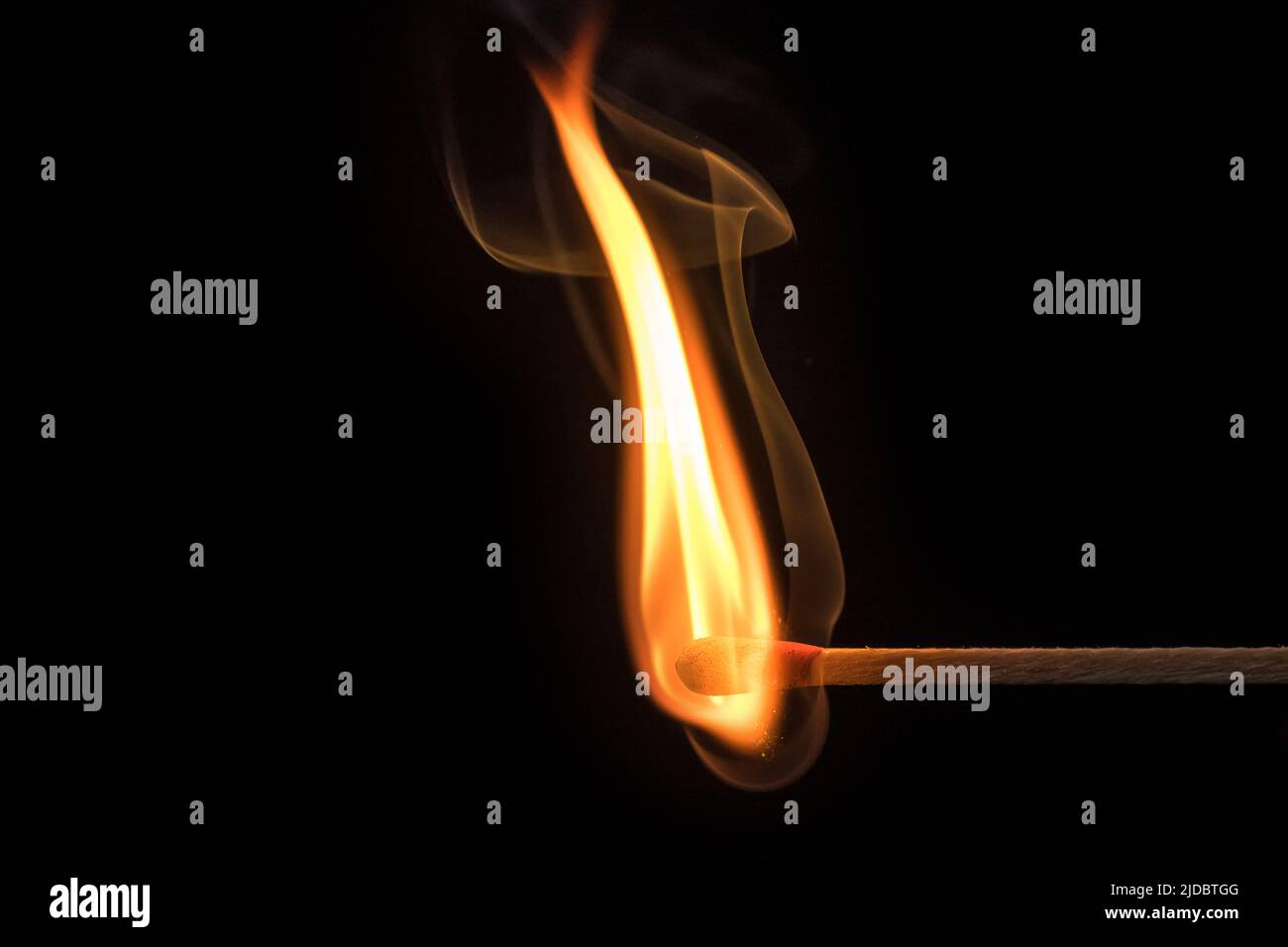 Fiamma ricurva e fumo di un fiammifero illuminato davanti a uno sfondo nero Foto Stock