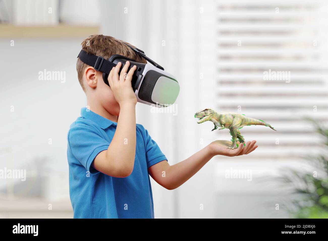 Ragazzo con occhiali VR proietta un dinosauro sul braccio. Il concetto di utilizzare la realtà virtuale nell'istruzione Foto Stock