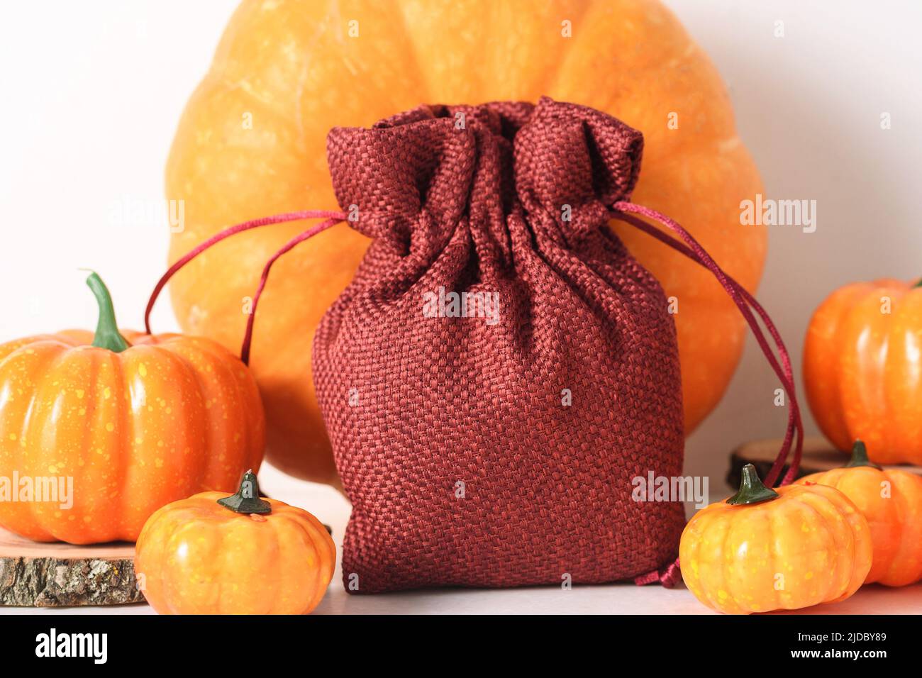 Borsa regalo vuota di iuta rosso scuro e molti puppini su un tavolo di marmo bianco, mockup caduta per il vostro disegno. Autunno, Halloween e concetto di ringraziamento Foto Stock