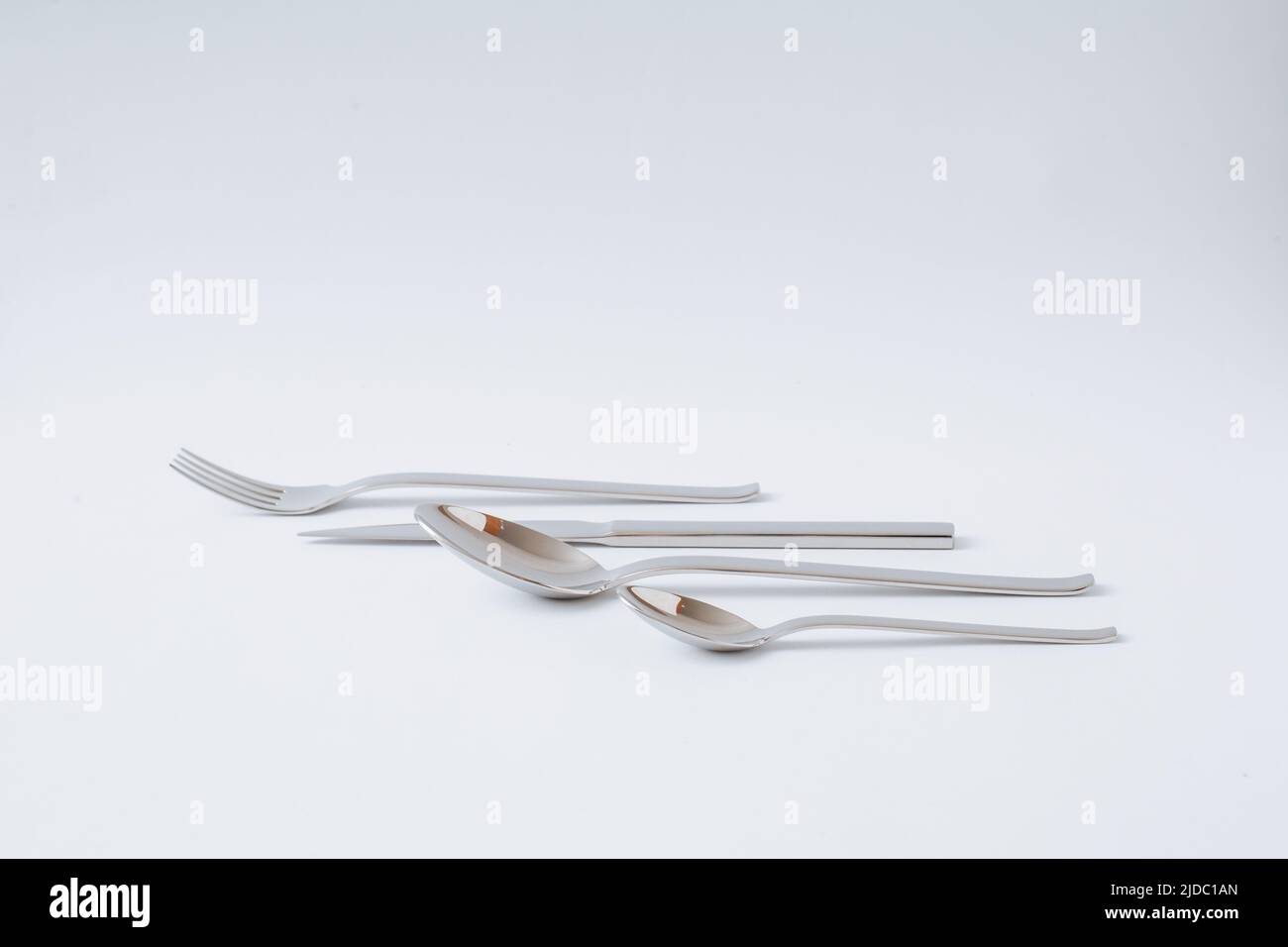 Set di posate in acciaio inox, coltello, cucchiaio, forchetta, cucchiaino su sfondo bianco, spazio copia. Foto Stock