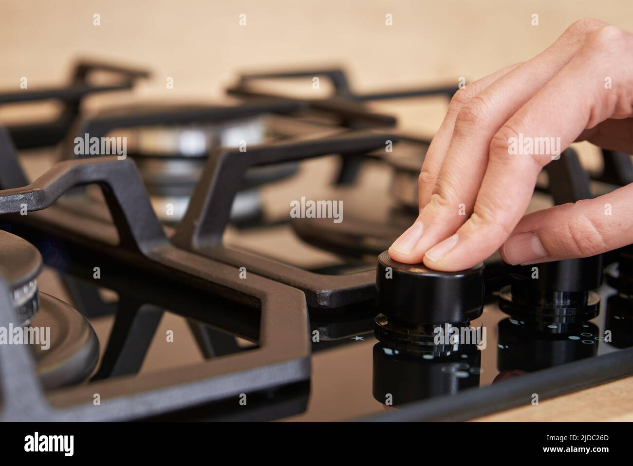 Regolazione della temperatura a mano femmina sul pannello di controllo del piano cottura a gas, donna con stufa a gas, elettrodomestici moderni Foto Stock