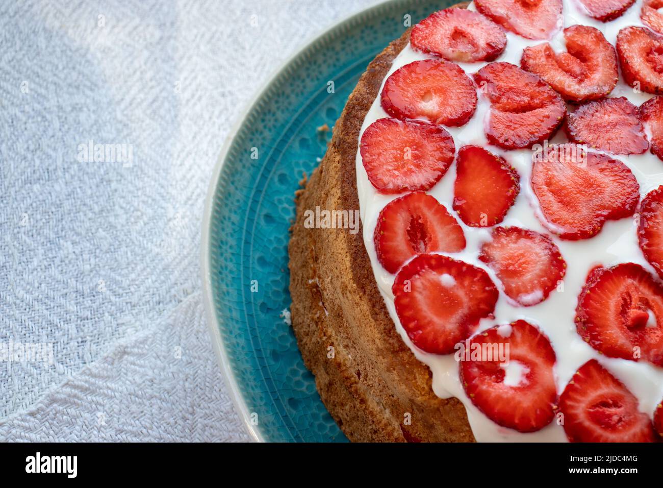 Torta con fragole e panna su piatto blu. Torta con strato di fragole estiva su sfondo bianco. Foto Stock