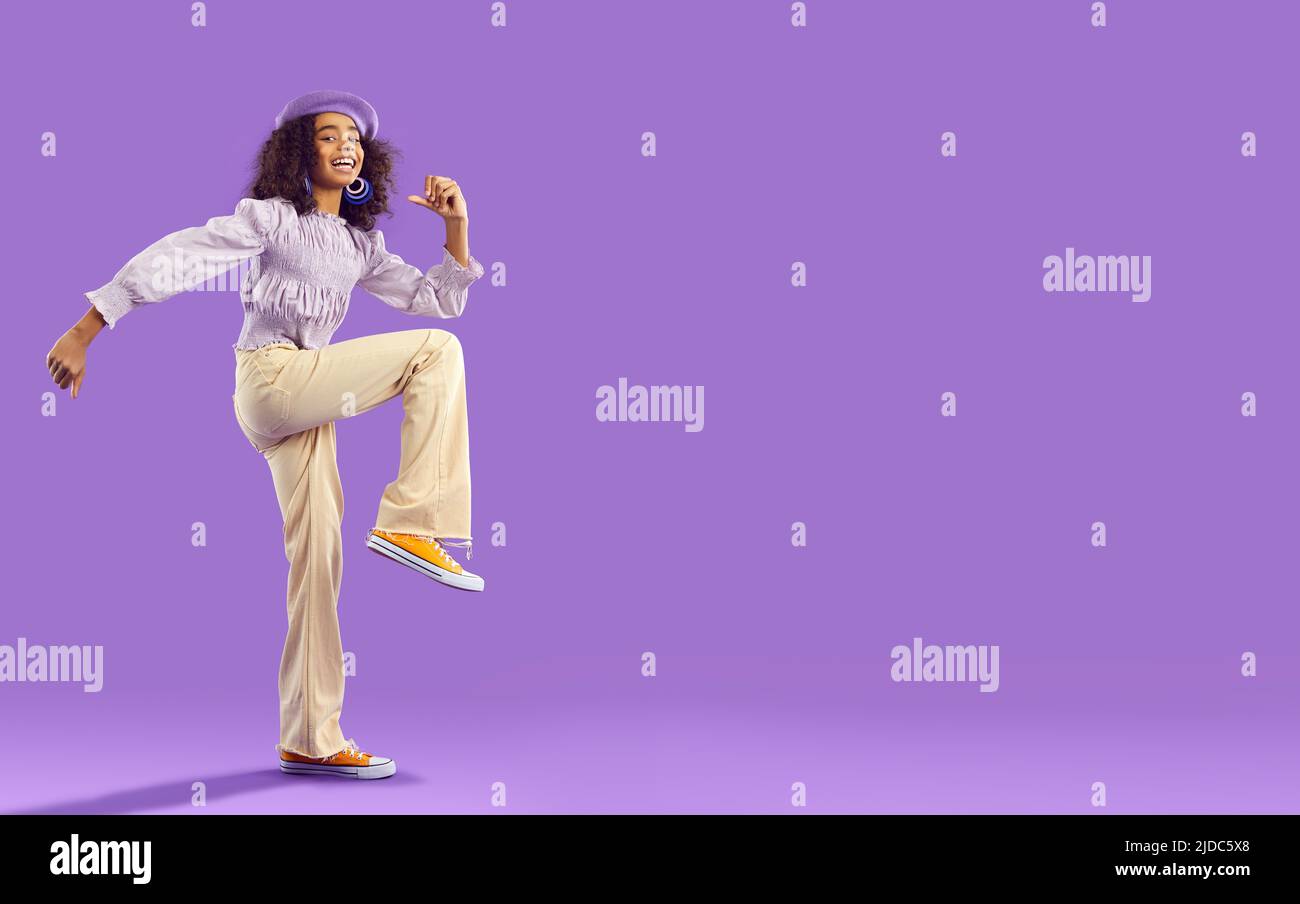 Sorridente afroamericana elegante teen girl che ha divertimento isolato su sfondo viola chiaro. Foto Stock